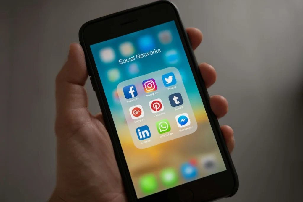 En hånd som holder opp en mobil med ikoner til sosiale medier-apper