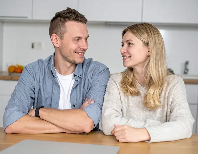 Glad par på kjøkkenet - ser på hverandre og smiler
